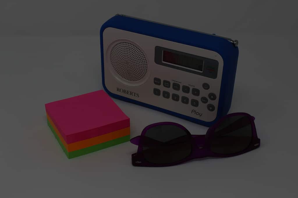 What is Shutter Speed in Photography? Underexposed still life. Blue radio, coloured sticky notes, purple sunglasses.