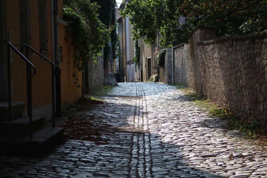 What is Aperture in Photography? Rustic cobbled village back alley partially lit by dappled sunlight.