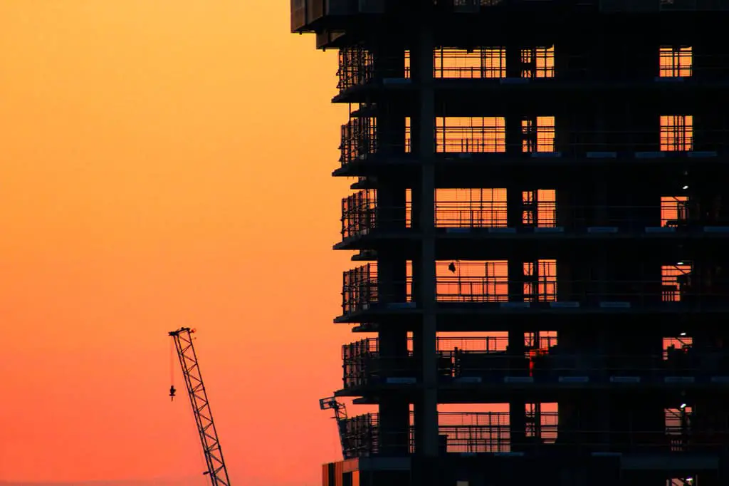 What is Composition in Photography? Building structure and crane silhouetted against an orange sunset sky.
