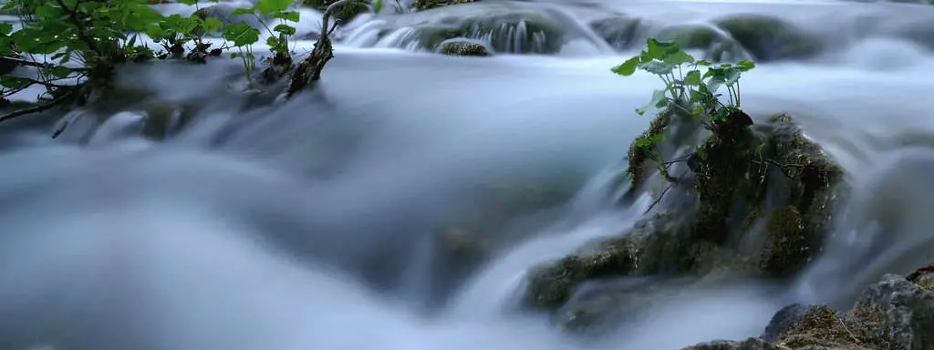 What Are ND Filters in Photography?   Slow shutter blurred river with rocks.