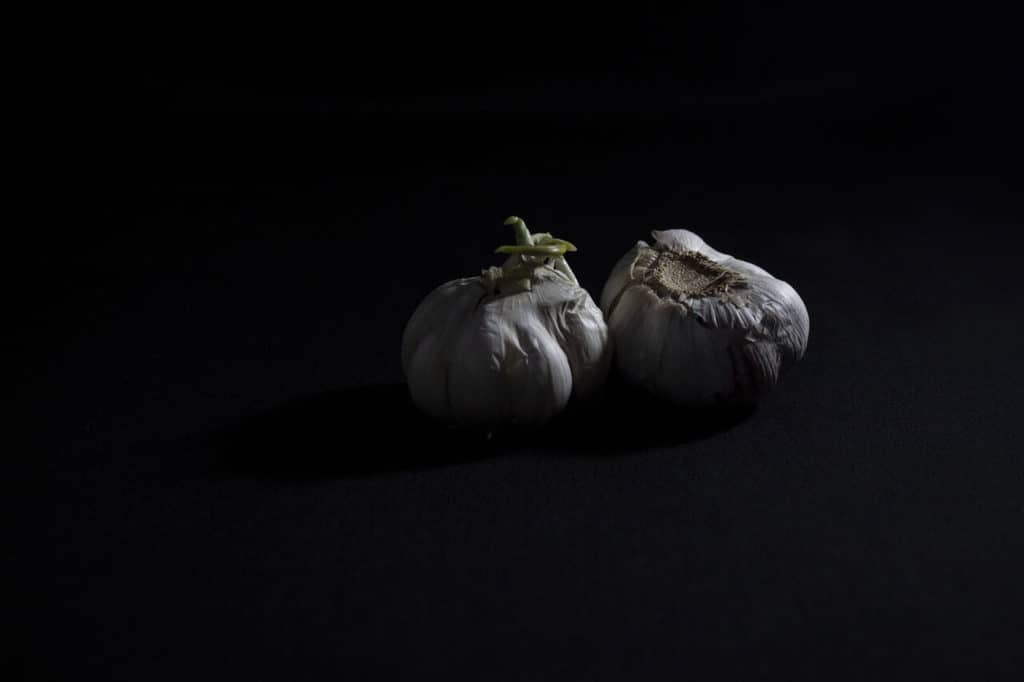 How to Take Low Key Photos Indoors And Outdoors! Underexposed wrinkled garlic bulbs in a dark box.