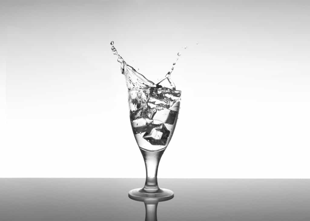 Ice Cube Splash Photography. Glass of water on a plexiglas sheet.