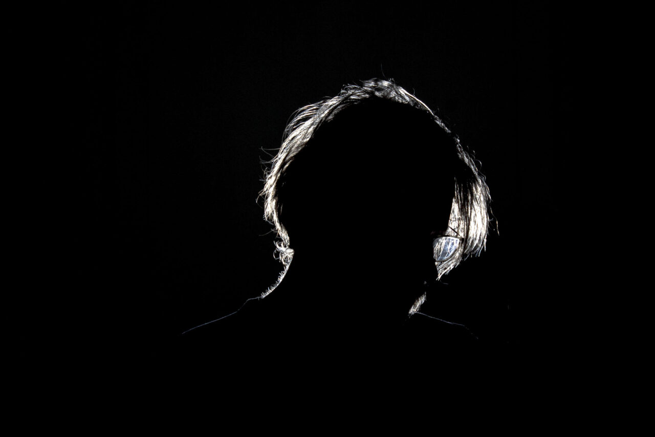 Low-key rim lit male subject with fluffy hair on black background