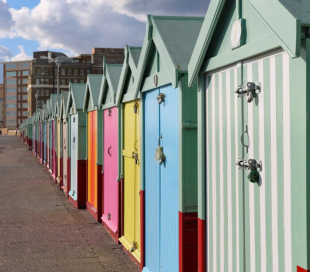 A row of multi colored beach huts receding into the distant perspective.